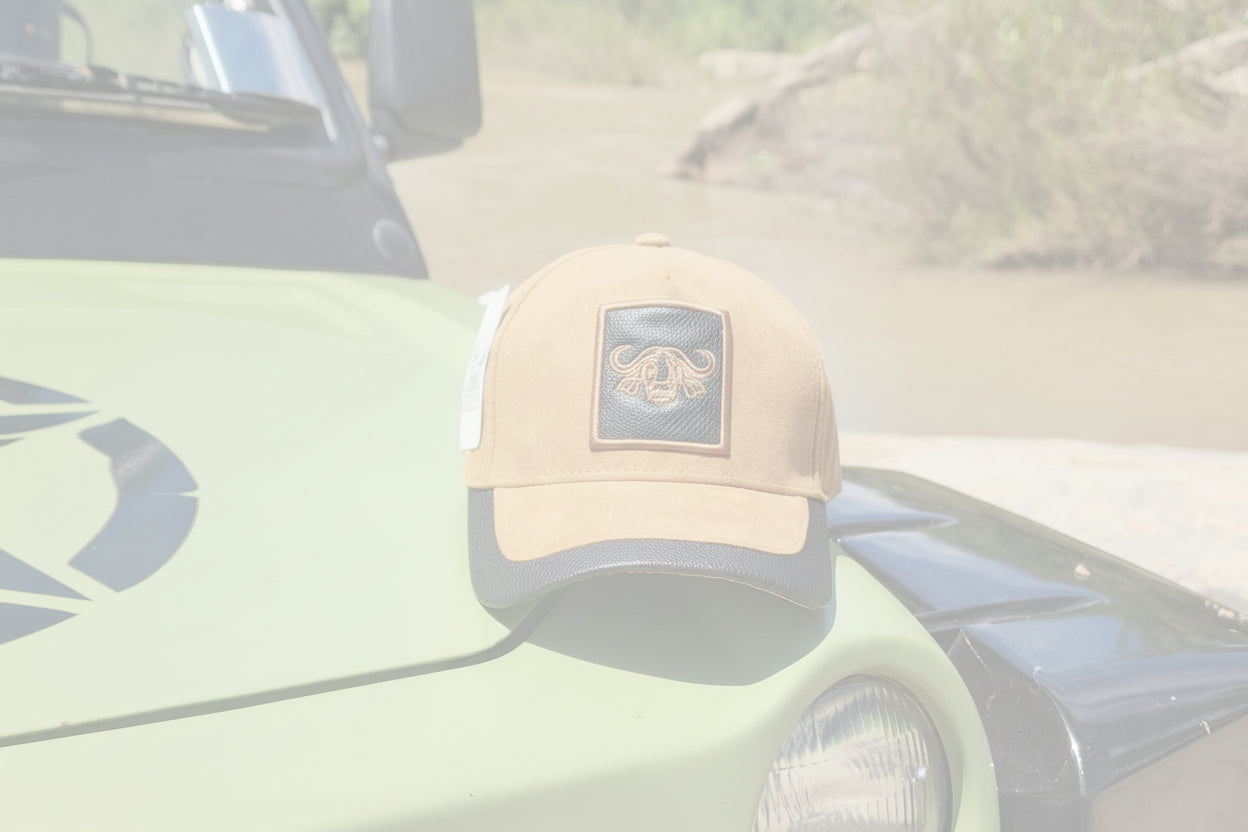 Tan baseball cap with a logo on a green vehicle by a river